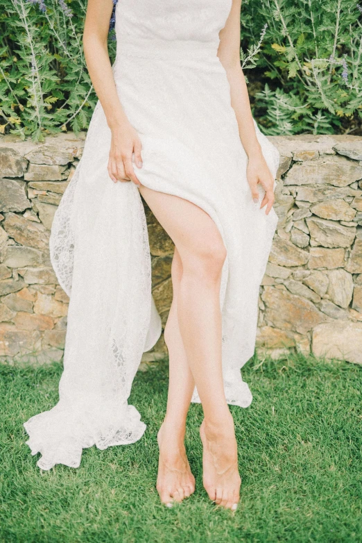 a woman sitting on top of a lush green field, by Will Ellis, renaissance, wearing heels and white dress, stand on stone floor, wedding, bare leg