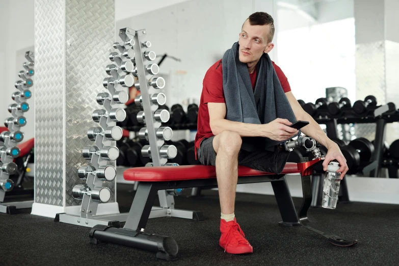 a man sitting on a bench in a gym, red and grey only, product introduction photos, high quality upload, multiple stories