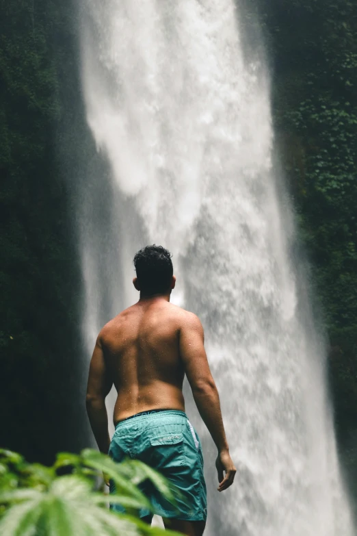 a man standing in front of a waterfall, super buff and cool, bali, viewed from behind, embarrassing