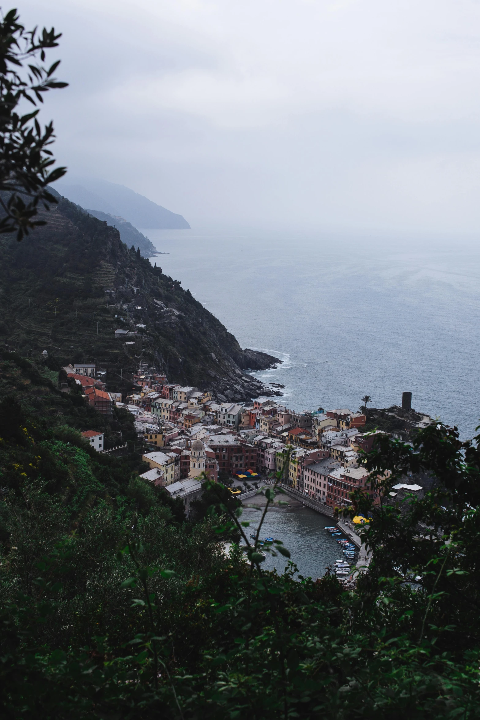 a large body of water next to a lush green hillside, inspired by Thomas Struth, unsplash contest winner, renaissance, cinq terre, mist below buildings, overcast dusk, views to the ocean