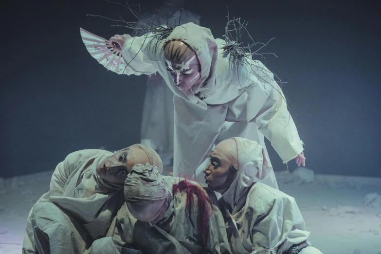 a group of people standing next to each other on a stage, inspired by Yoshitoshi Mori, baroque, performing to dead soldiers, heilung, white robes, 3 figures as winter spirits