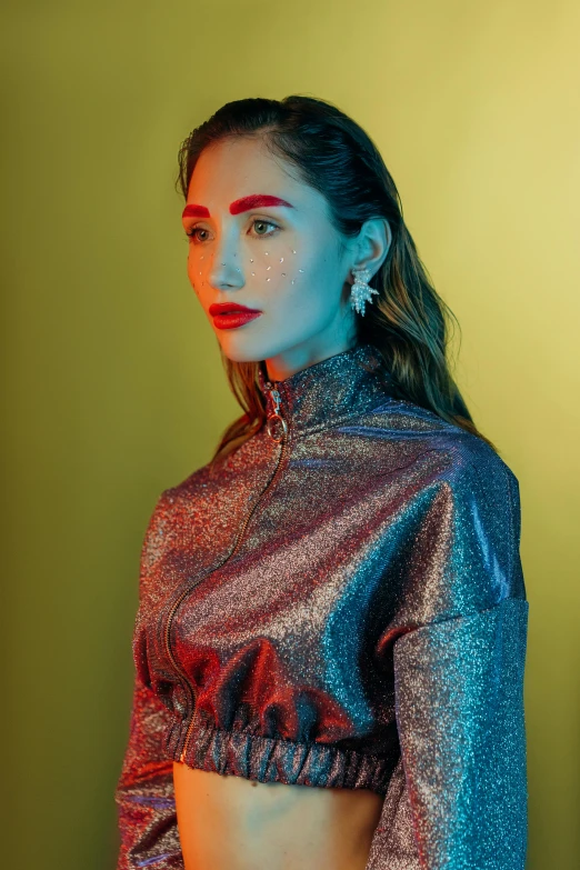 a woman standing in front of a green wall, an album cover, inspired by Elsa Bleda, trending on pexels, holography, gal gadot portrait, silver gold red details, cinematic outfit photo, close - up studio photo