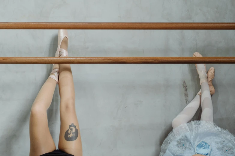 a couple of women standing next to each other, a tattoo, inspired by Elsa Bleda, trending on pexels, arabesque, dressed as a ballerina, balance beams, top-down shot, sitting on a stool