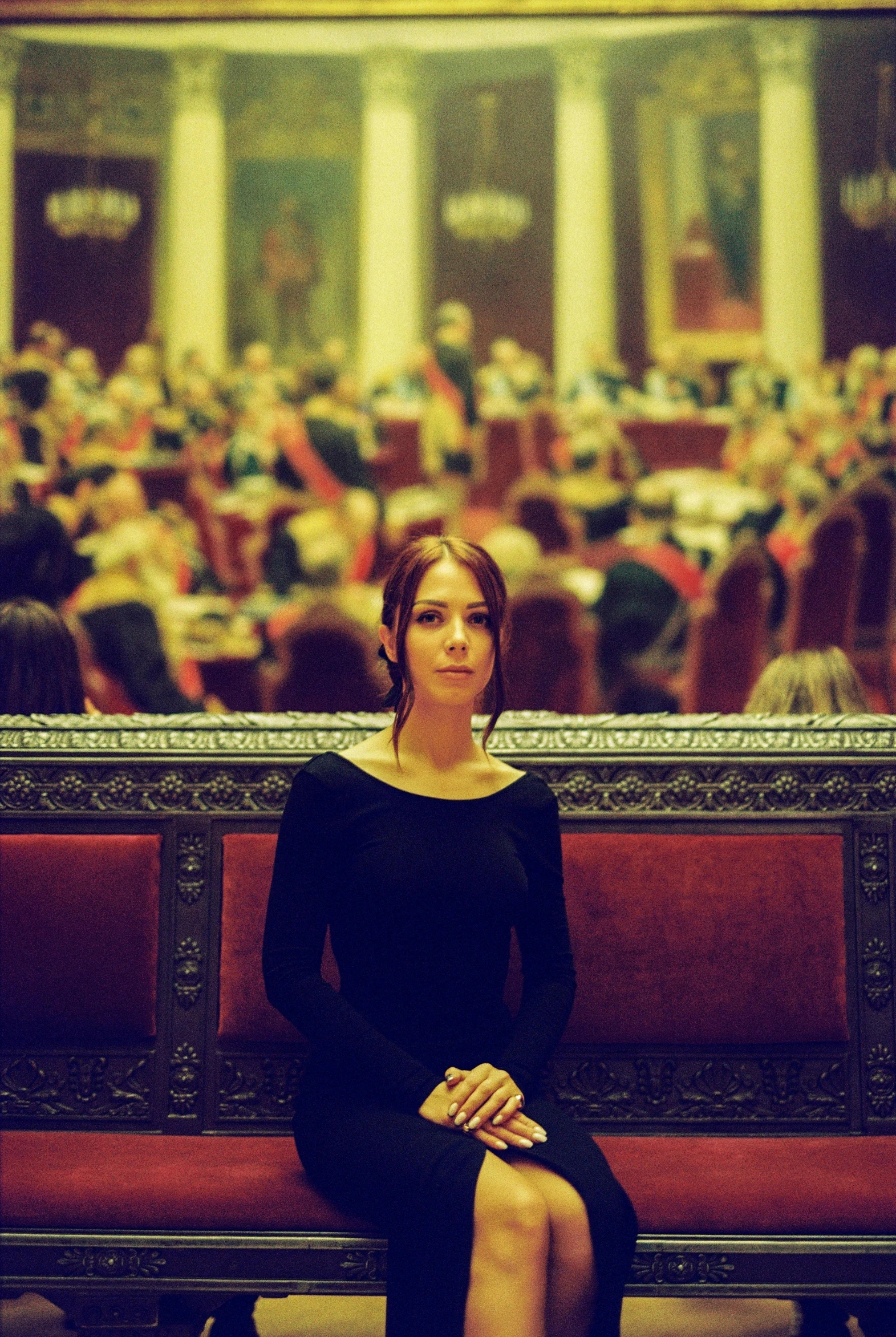 a woman sitting on a bench in front of a painting, an album cover, inspired by Anka Zhuravleva, pexels contest winner, renaissance, sitting at the parlament meeting, standing in a restaurant, moody::alejandro jodorowsky, as cristina kirchner