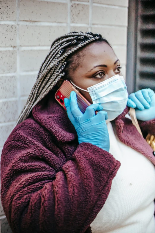 a woman in blue gloves talking on a cell phone, a photo, by Kristin Nelson, trending on pexels, masked doctors, african american, with wires and bandages, brown