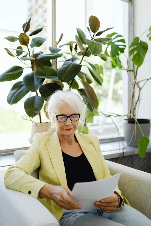 a woman sitting in a chair reading a piece of paper, by Sigrid Hjertén, trending on unsplash, modernism, plants in glasses, white-haired, woman made of plants, corporate boss