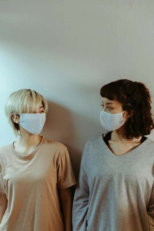 two women standing next to each other wearing face masks, by Adam Marczyński, grey, plain, brown, profile image