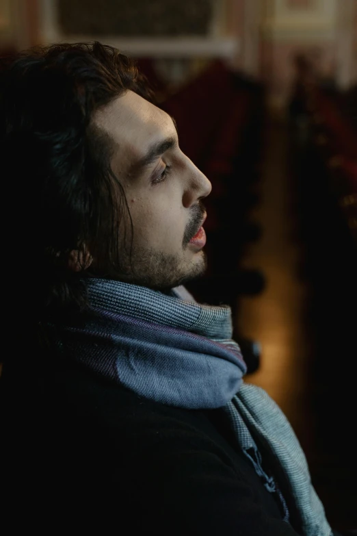 a man with long hair wearing a scarf, inspired by Pál Balkay, pexels contest winner, romanticism, movie still of a tired, concert, reza afshar, [ theatrical ]