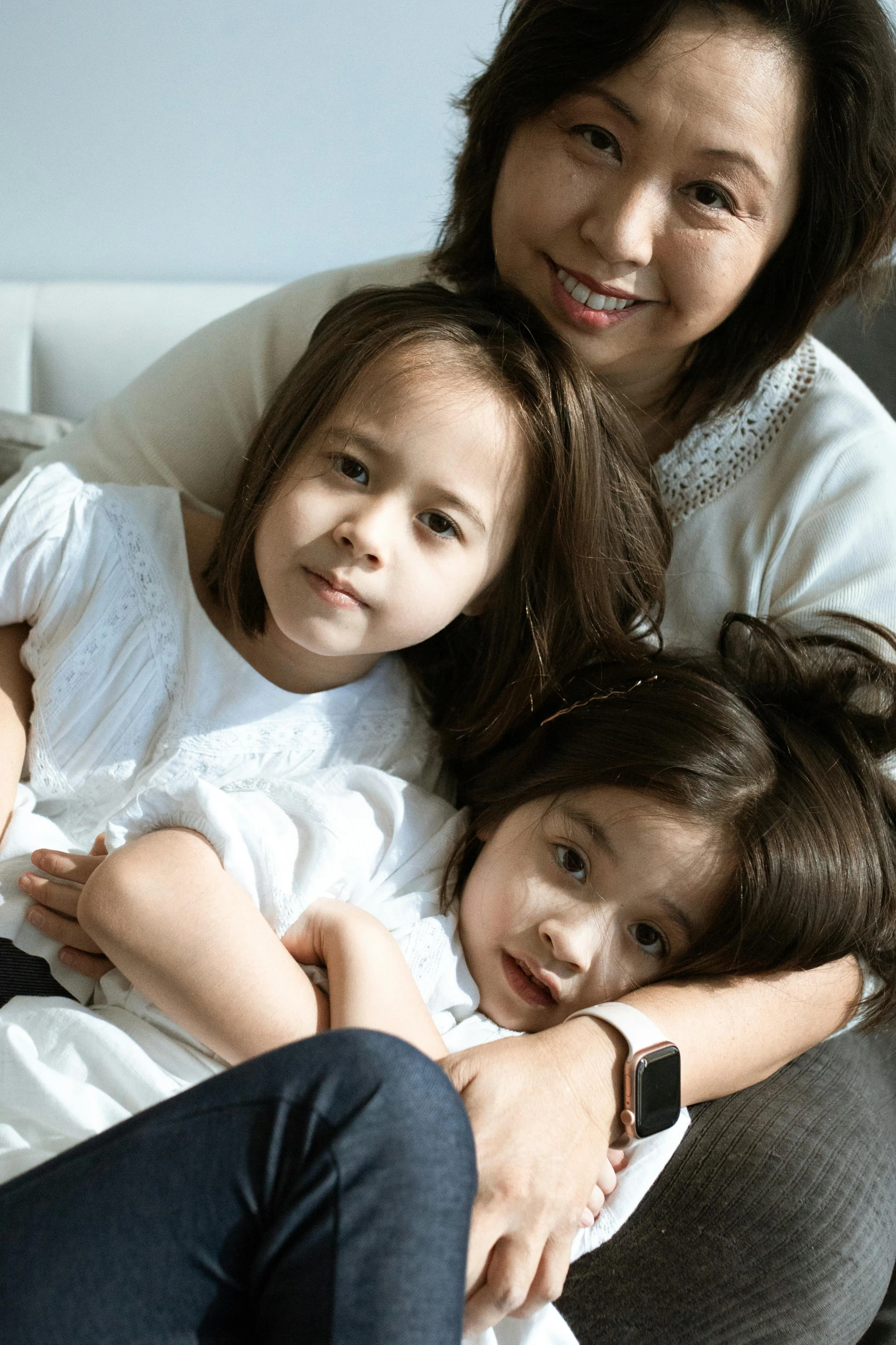 a woman and two children sitting on a couch, incoherents, asian descent, hugging and cradling, promo image, portrait image