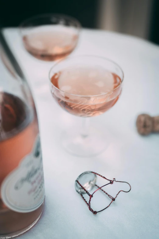 two glasses and a bottle of wine on a table, inspired by Jacopo Bellini, pexels contest winner, rose, organic detail, trinkets, neck zoomed in