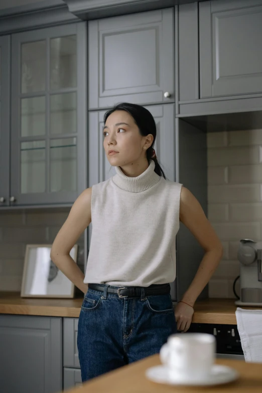 a woman standing in a kitchen next to a counter, inspired by Kim Tschang Yeul, trending on unsplash, hyperrealism, sleeveless turtleneck, low quality photo, androgynous person, mariko mori