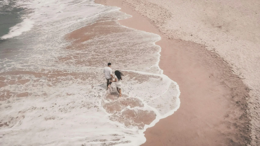 a man riding a surfboard on top of a sandy beach, by Arabella Rankin, pexels contest winner, renaissance, man and woman walking together, pink, taking from above, grey