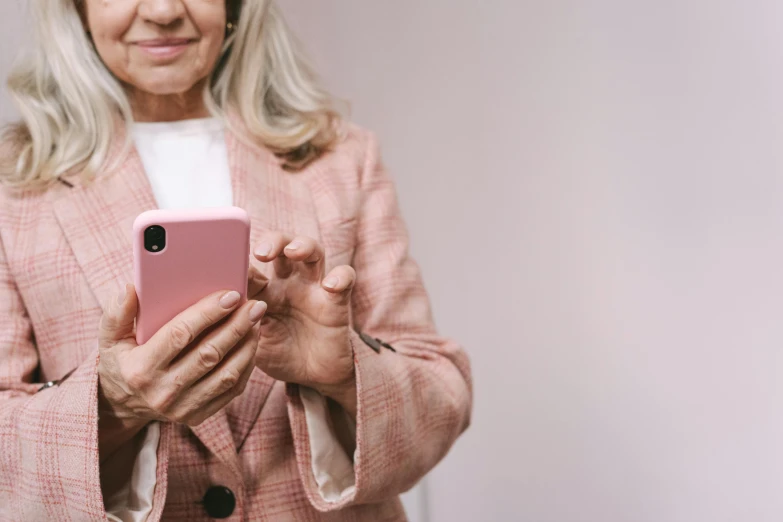 a close up of a person holding a cell phone, pink clothes, older woman, pleasing aesthetics, woman in business suit