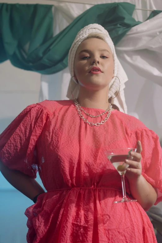 a woman in a red dress holding a glass of wine, an album cover, inspired by Sophia Beale, wearing a white bathing cap, video still, official screenshot, youtube thumbnail
