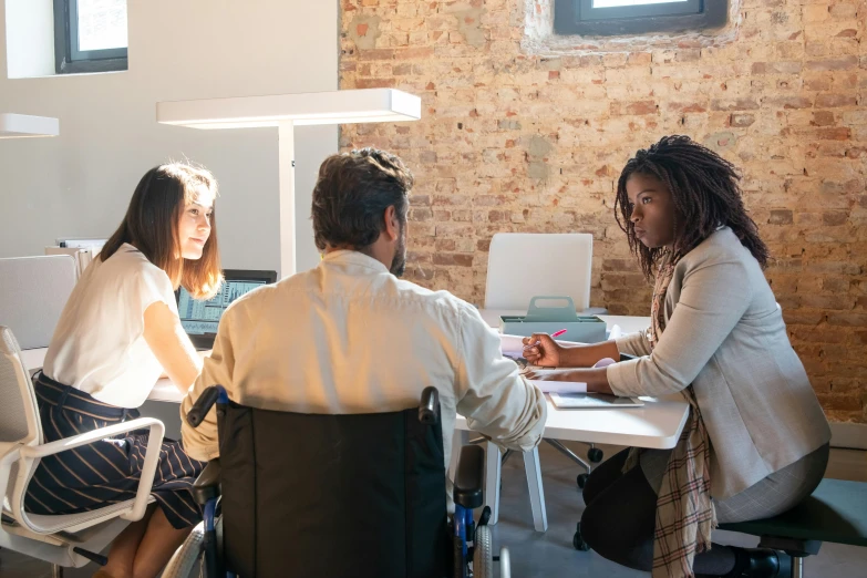 a couple of people that are sitting at a table, trending on unsplash, renaissance, sitting in a wheelchair, in a meeting room, avatar image, brown