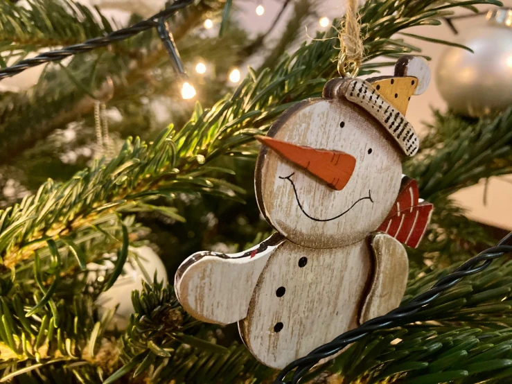 a wooden snowman ornament hanging from a christmas tree, inspired by Ernest William Christmas, pexels contest winner, 🦩🪐🐞👩🏻🦳, smug smile, shot with sony alpha, various posed