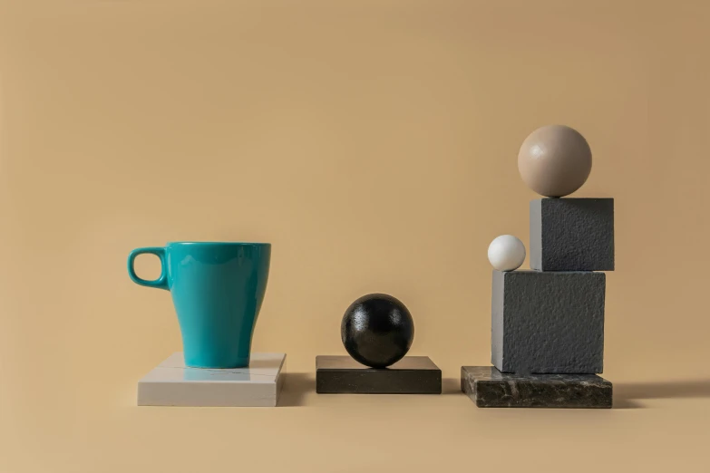 a coffee cup sitting on top of a wooden block, an abstract sculpture, inspired by Bauhaus, cups and balls, teal, ashford black marble sculpture, detailed product image