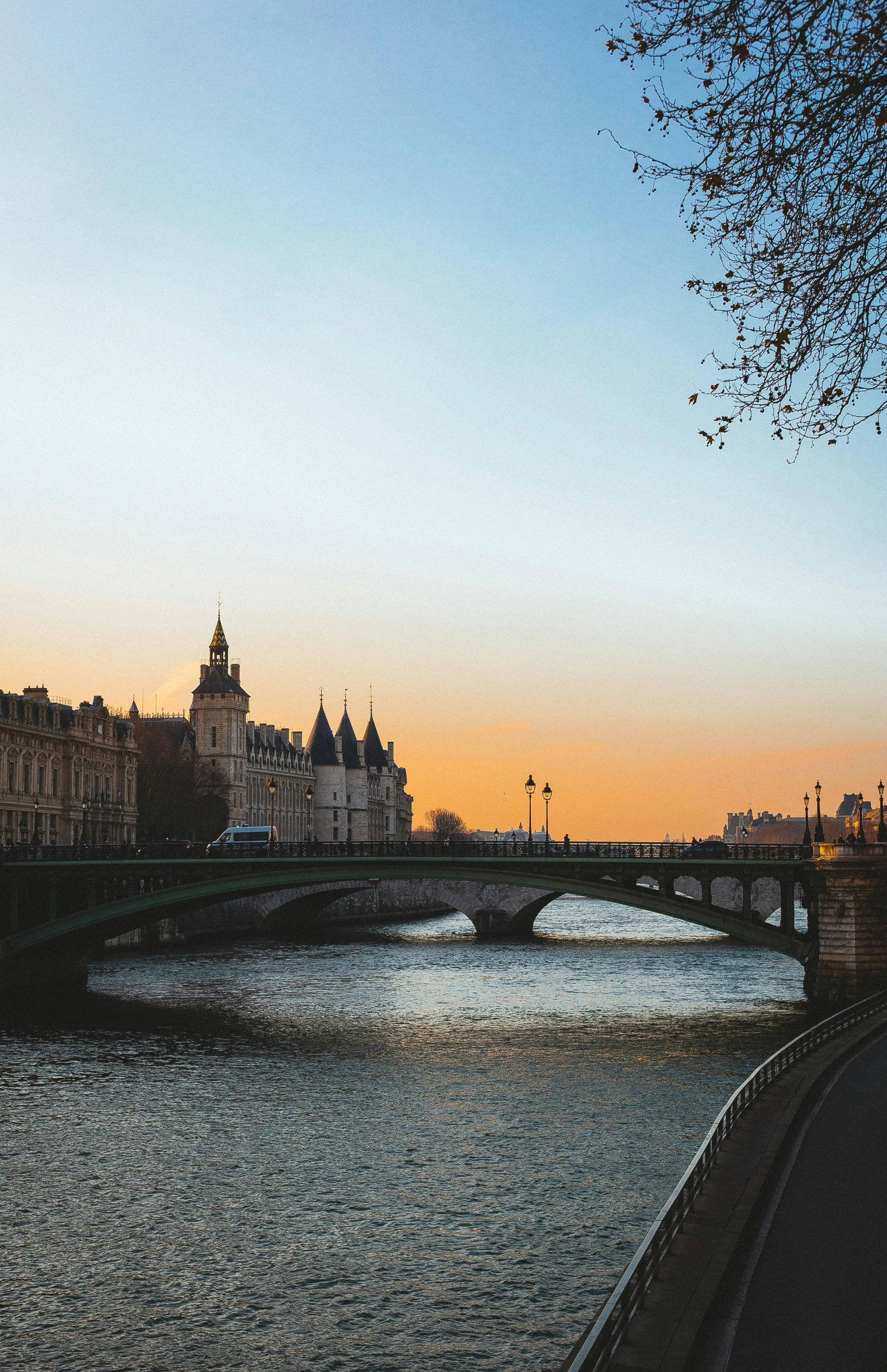 a bridge over a river with buildings in the background, pexels contest winner, paris school, calm evening, golden hour hues, parliament, february)