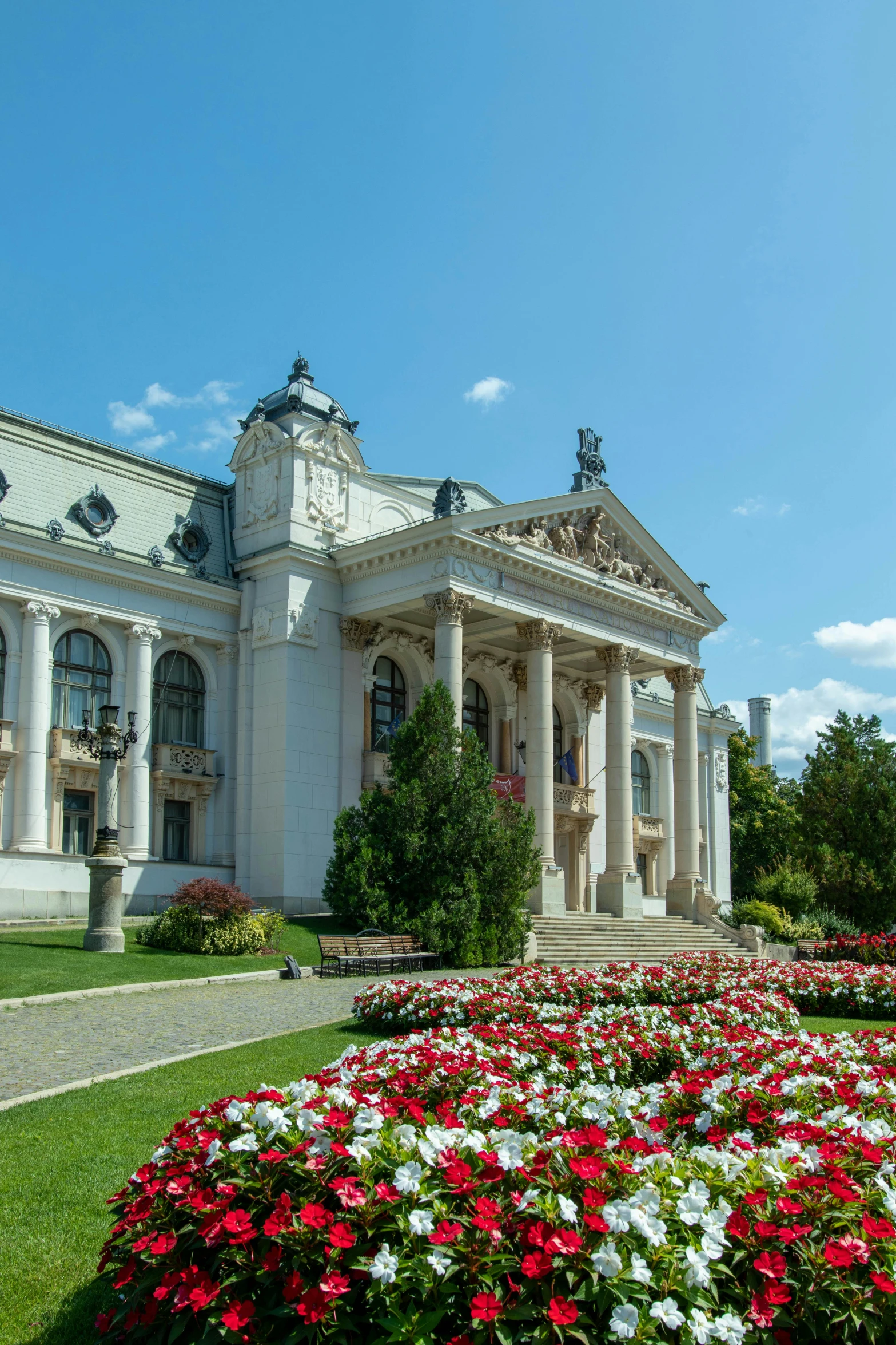 a large white building sitting on top of a lush green field, by Bertalan Székely, grand library, flowerbeds, theater, town hall