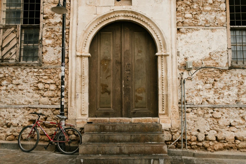 a bicycle parked in front of a stone building, pexels contest winner, romanesque, door, conversano, orthodox, brown