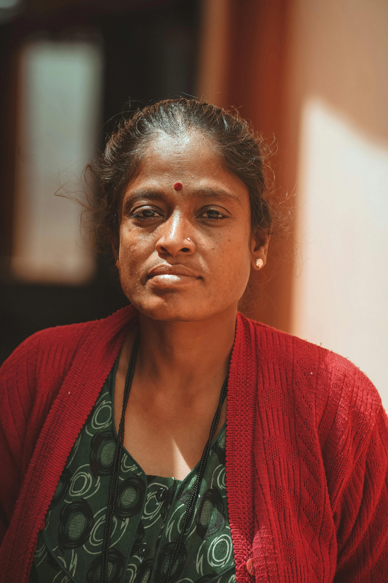 a woman in a green dress and red cardigan, a portrait, by Max Dauthendey, pexels contest winner, sri lanka, close-up portrait film still, brown, 4 0 - year - old