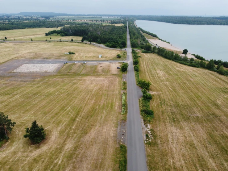 an aerial view of a road next to a body of water, by Matthias Stom, unsplash, land art, ai weiwei and gregory crewdson, battlefield in background, france, 2 0 2 2 photo