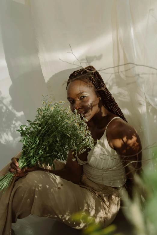 a woman sitting on the ground holding a bunch of flowers, by Dulah Marie Evans, lupita nyong'o, indoor picture, herbs, covered in vines