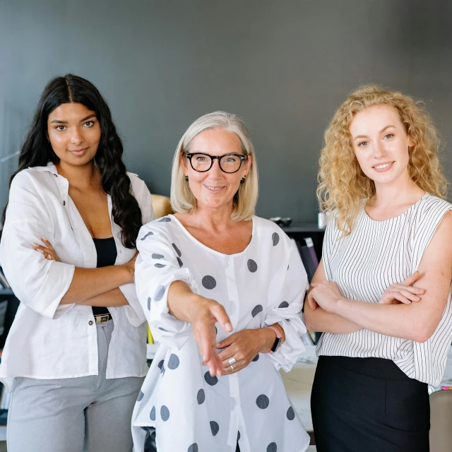 a group of three women standing next to each other, pexels contest winner, people at work, white woman, confident stance, reaching out to each other