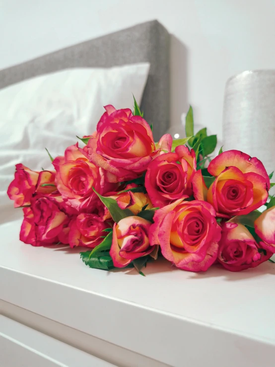 a bunch of red roses sitting on top of a white dresser, toned orange and pastel pink, lying in bed, pink and yellow, infused with aurora borealis