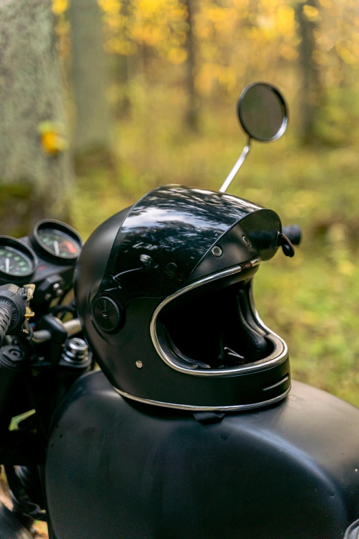 a close up of a motorcycle with a helmet on, a portrait, by Sven Erixson, unsplash, panorama shot, lush surroundings, black, a wooden