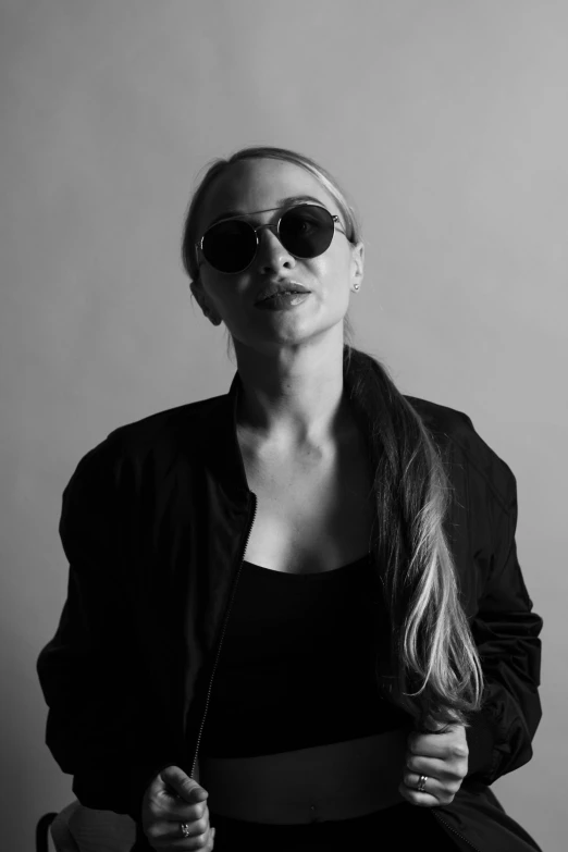 a black and white photo of a woman wearing sunglasses, inspired by Ilka Gedő, wearing black clothes, a girl with blonde hair, arms folded, resembling a mix of grimes