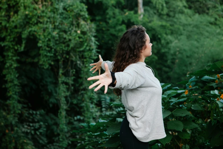 a woman is throwing a frisbee in the air, unsplash, happening, insectile forearms folded, foliage clothing, tai chi, looking across the shoulder