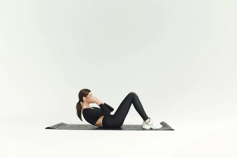 a woman doing an exercise on a yoga mat, by Emma Andijewska, modelling, black, in front of white back drop, with abs