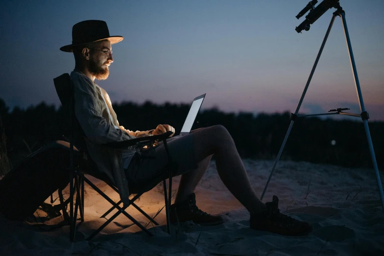 a man sitting in a chair using a laptop computer, trending on pexels, plein air, night time australian outback, avatar image, astronomical imaging, profile picture