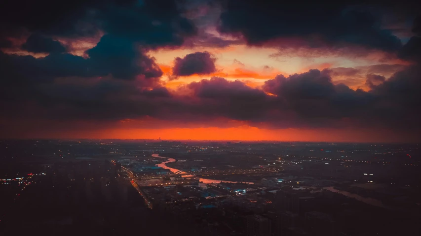 an aerial view of a city at sunset, by Adam Marczyński, pexels contest winner, happening, night clouds, red sunset, orange and cyan lighting, overcast dusk