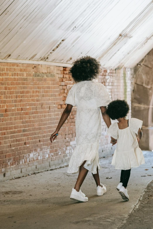 a woman and a little girl walking down a sidewalk, pexels contest winner, black arts movement, nico wearing a white dress, standing in abandoned building, off - white collection, afropunk