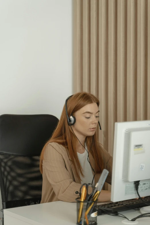 a woman sitting at a desk in front of a computer, trending on pexels, wearing headset, a redheaded young woman, slightly pixelated, brown