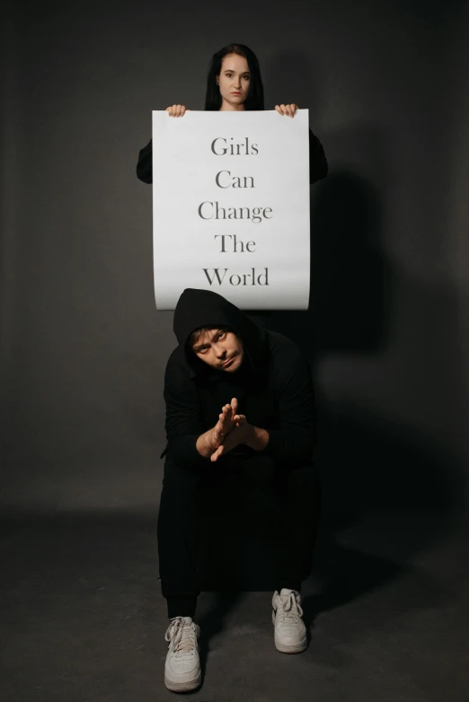 a woman holding a sign that says girls can change the world, an album cover, pexels contest winner, riyahd cassiem, full body photoshoot, profile image, girl wearing hoodie