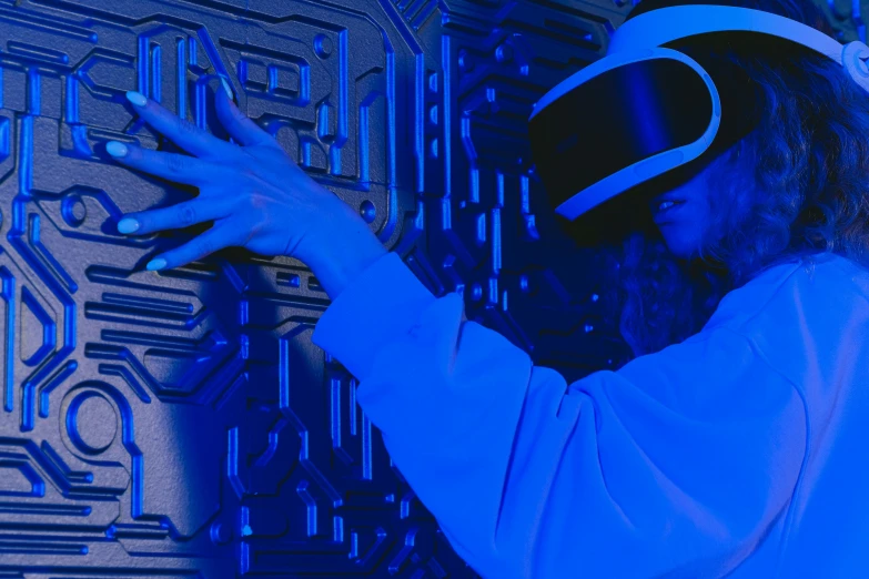 a close up of a person wearing a virtual reality headset, inspired by Leng Mei, interactive art, brightly lit blue room, tech robes, maze, cybernetic hands