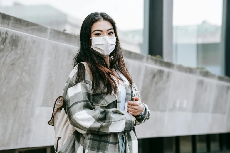 a woman wearing a face mask standing in front of a building, trending on pexels, happening, asian girl with long hair, masked doctors, background image, with a backpack