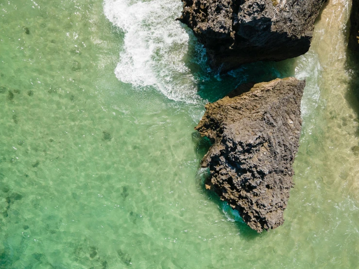 a couple of large rocks sitting on top of a body of water, pexels contest winner, minimalism, bird's view, gold coast australia, green water, youtube thumbnail