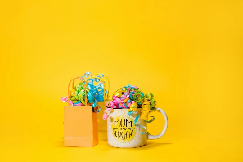two coffee mugs sitting next to each other on a yellow background, pexels contest winner, with an easter basket, wrapped in wires and piones, pop figure of mom with long, background image