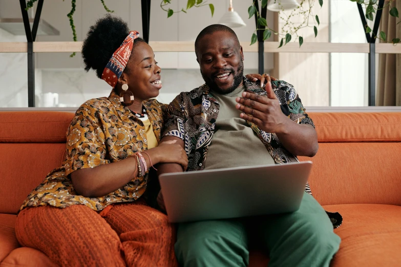 a man and woman sitting on a couch looking at a laptop, pexels, afrofuturism, earing a shirt laughing, thumbnail, patterned clothing, tv still