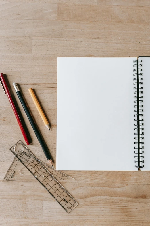 an open notebook sitting on top of a wooden table, a drawing, trending on pexels, pencils, white space in middle, unfinished canvas, product introduction photo