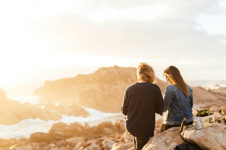 two people sitting on a log looking out at the ocean, trending on pexels, flowy hair standing on a rock, warm light, australian, walking together