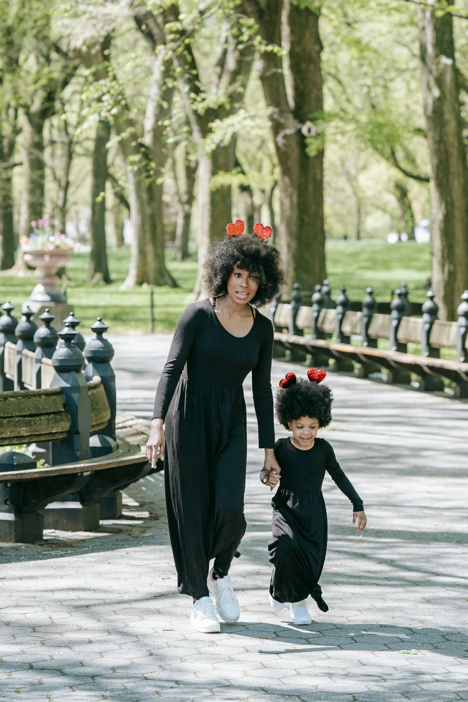 a woman and a child walking in a park, with afro, wearing a black dress, humans of new york style, long black crown