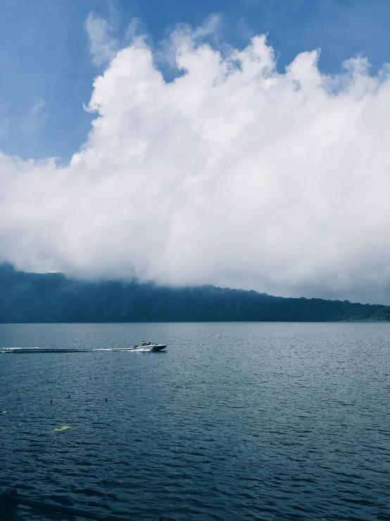 a boat in the middle of a large body of water, by Carey Morris, pexels contest winner, sumatraism, covered in clouds, 2 5 6 x 2 5 6 pixels, lakeside, wall of water either side