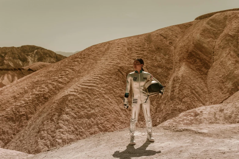 a man in a space suit walking across a desert, a colorized photo, unsplash, renaissance, sophia lillis, wearing shiny gold catsuit, mars vacation photo, wearing a spacesuit and helmet