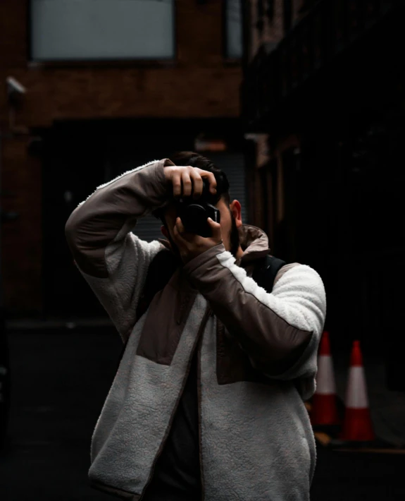 a man taking a picture with a camera, by Robbie Trevino, wearing hoodie, non-binary, ((sharp focus))