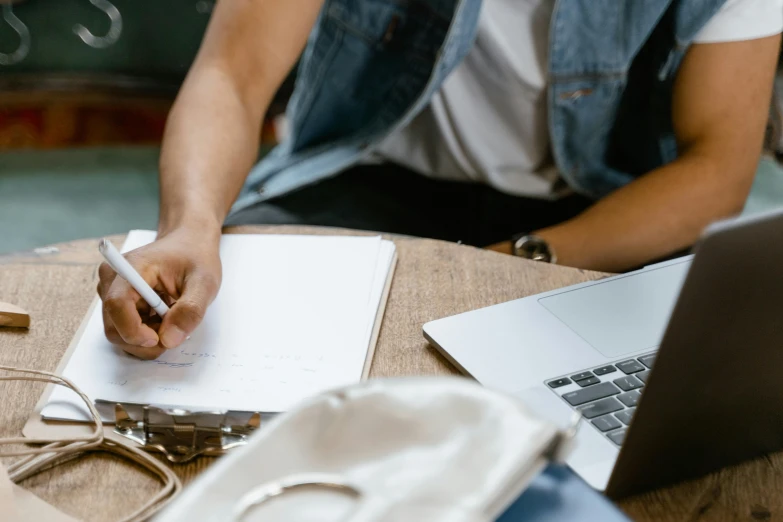 a man sitting at a table writing on a piece of paper, a drawing, trending on pexels, working on her laptop, schools, casually dressed, thumbnail